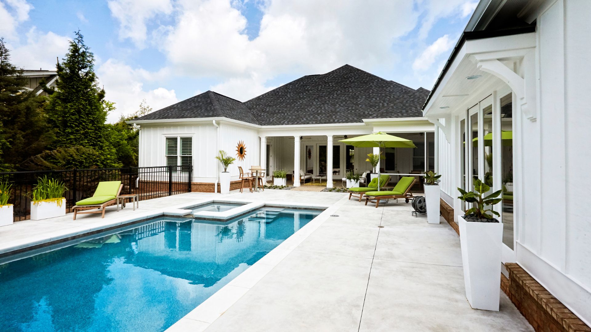 Luxurious white house with blue swimming pool and green lounge chairs
