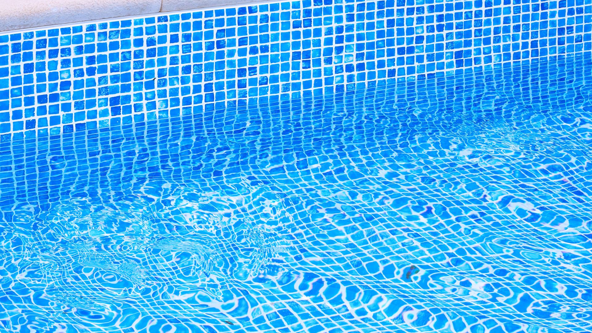 Blue swimming pool tiles with rippling water creating distorted mosaic pattern