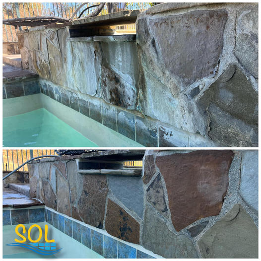 Stone wall with irregular rocks beside blue-green tiled water feature