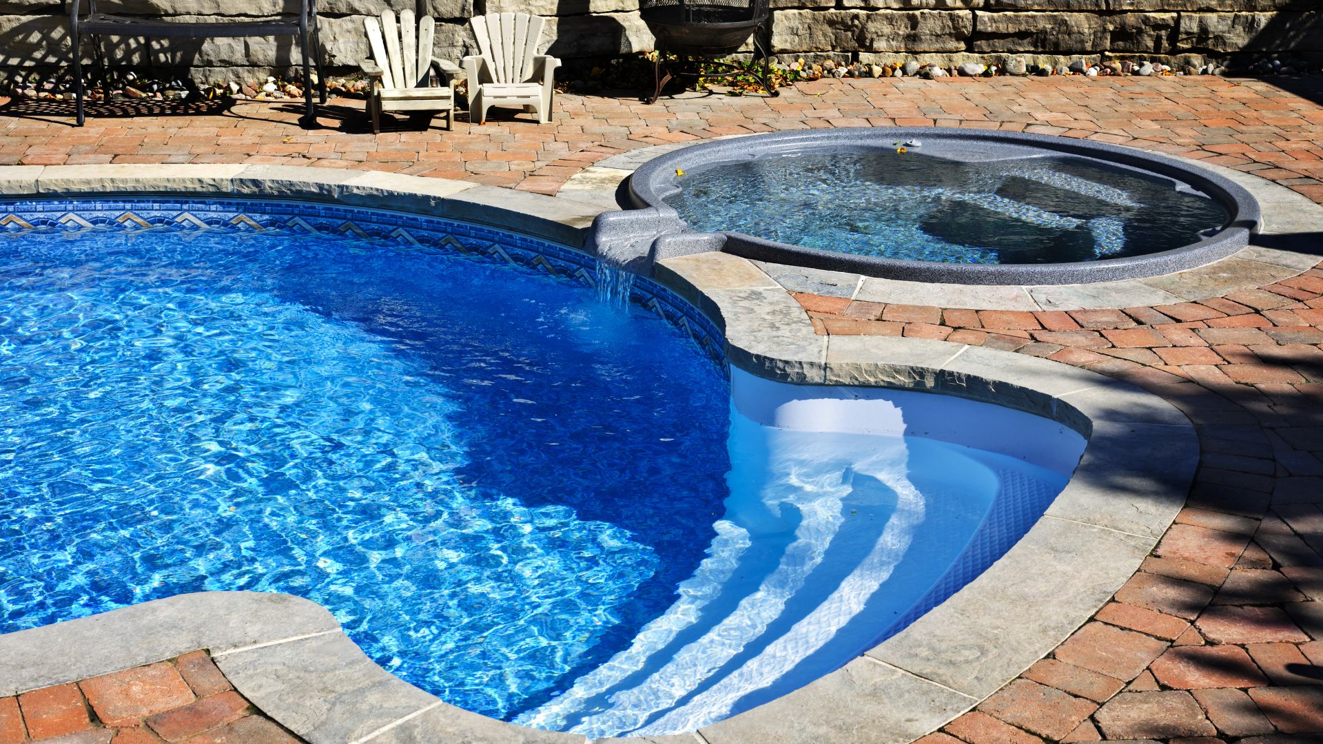 Backyard swimming pool with curved steps and adjacent round hot tub